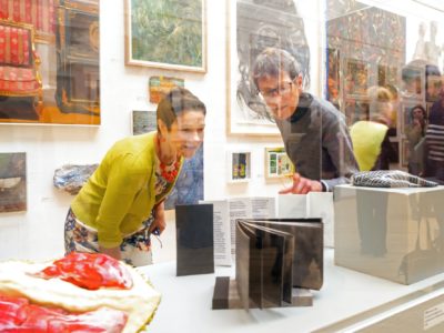 Woman and man look at object inside an exhibition glass case
