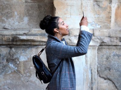 A woman takes a photograph on a smartphone at a heritage site.