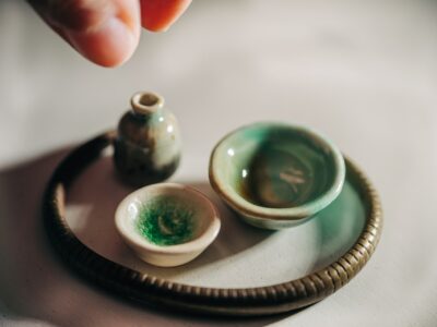 Two small ceramic bowls and a small ceramic container sit on a dish.