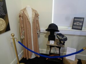 An Edwardian coat and hat behind a velvet rope